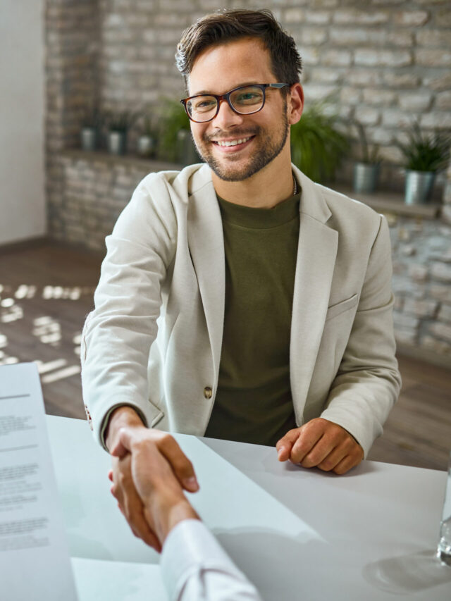 Young happy man shaking hands with a businessman on a job interv