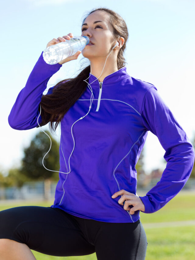 Pretty young woman drinking water after running.