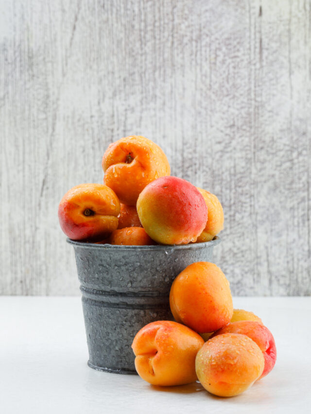 Ripe apricots in a mini bucket on white and grunge background. side view.