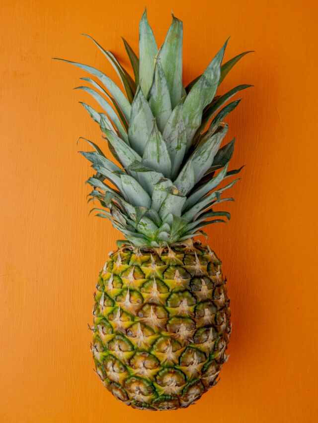 side view of pineapple on orange background